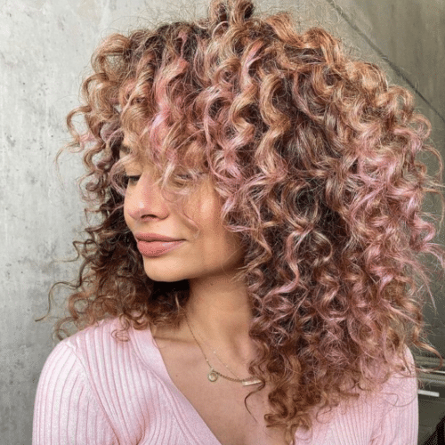 Woman with dark curly hair with light pink ends