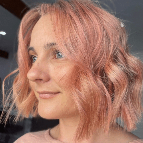 Woman with shoulder length, wavy, peach coloured hair